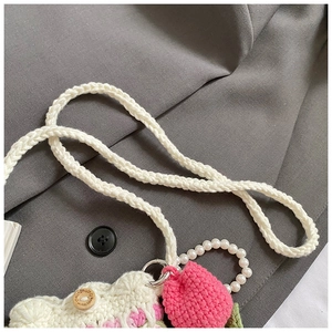 Detail of handmade crochet shoulder bag with strawberry charm and pearl handle