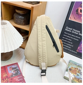 Detail of cream kids chest bag with brown side panel and black plastic buckle closure