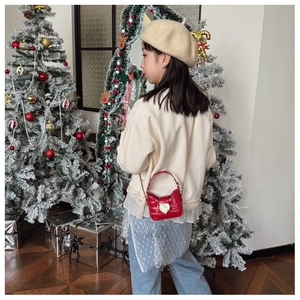 Detail of red crocodile texture kids bag with golden heart buckle and chain strap
