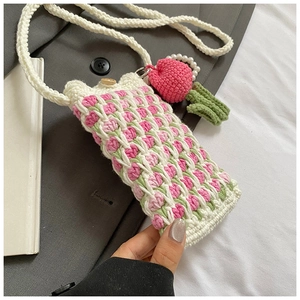 Detail of handmade crochet shoulder bag with tulip patterns and strawberry pendant