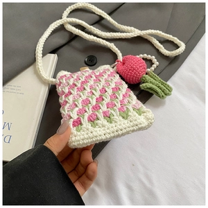 Close-up of handmade crochet crossbody bag with tulip patterns and strawberry charm