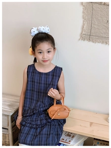 Detail of brown leather mini bag for kids featuring a sweet bow and golden heart charm