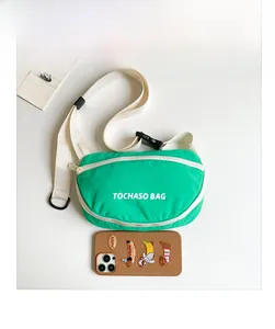 Grüne Nylon-Gürteltasche mit TOCHASO-Schriftzug neben Handyhülle für den Größenvergleich