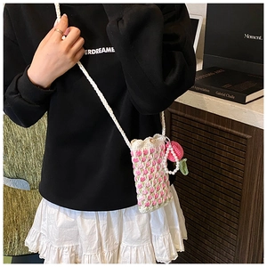 Detailed view of handmade crochet crossbody bag with pink floral patterns and pearl strap