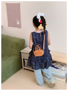 Detail of a brown kids crossbody bag with bow decoration shown on a young model