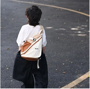 Outdoor view of child wearing a color-block canvas chest bag with adjustable strap