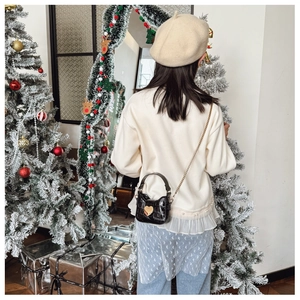 Kid's mini black croc-effect bag with gold heart detail shown in a festive holiday scene