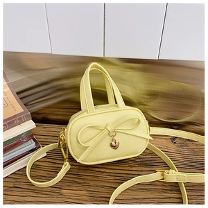 Detail of yellow mini handbag featuring a sweet bow and golden heart pendant for kids