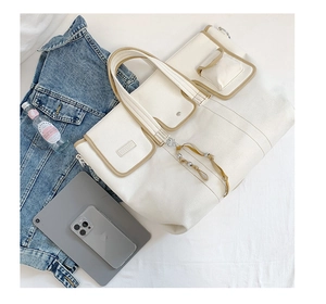 Detail of white canvas tote bag with multi-pocket design and brown leather piping trim