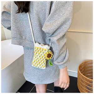 Close-up of handmade crochet bag featuring yellow tulip patterns and sunflower charm