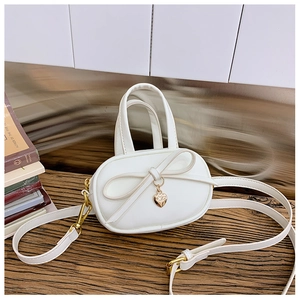 Detail of white mini handbag with golden heart pendant and bow on rustic wooden surface