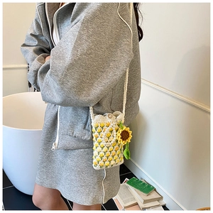 Detail of handmade crochet shoulder bag featuring yellow floral patterns and pearl buckle