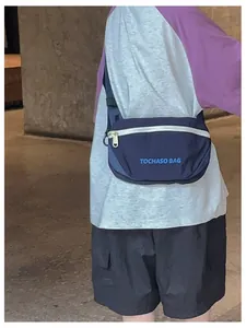 Detailansicht einer blauen Kinder-Brusttasche aus Nylon mit weißem Reißverschluss-Akzent