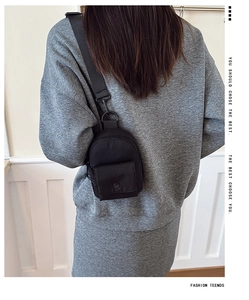 Rear view of a child wearing a mini black canvas crossbody chest bag over a grey hoodie