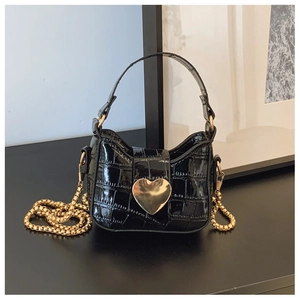 Detail of black faux crocodile skin texture and large gold heart clasp on mini bag