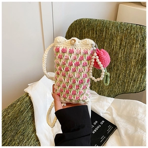 Close-up of handmade crochet bag featuring pink tulip patterns and a pearl strap