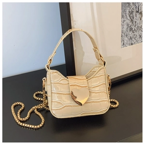 Close-up of cream beige crocodile pattern bag with golden heart clasp and chain strap