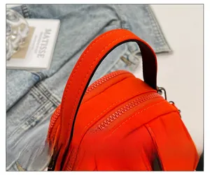 Detail showing the comfortable handle and nylon texture of the orange crossbody bag