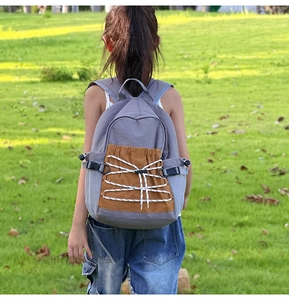 Outdoor view of children school bag featuring grey fabric and brown drawstring pocket
