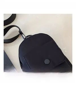 Close-up of black nylon mini chest bag with snap pocket and adjustable woven strap