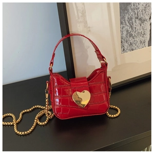 Macro detail of red faux crocodile leather with a gold heart buckle and chain strap