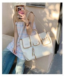 Detail of off-white tote bag with brown trim and front flap pockets for daily commuting