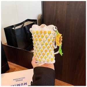 Close-up of handmade crochet bag with yellow tulip patterns and a sunflower charm