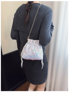 Detail of holographic sequin bucket bag with drawstring closure and gold chain strap
