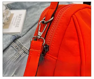 Detailed shot of bright orange fabric bag with silver metal swivel hook and zipper