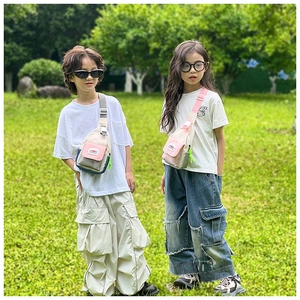 Outdoor view of two children wearing contrast color canvas chest bags with wide straps