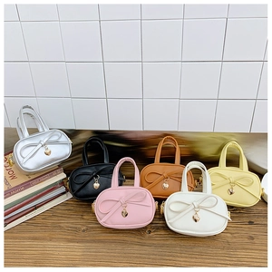 Flat lay of six colorful mini kid handbags with ribbon bows and golden heart charms