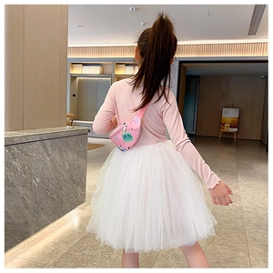 Détail du sac de poitrine rose avec motif cartoon porté par un enfant dans un grand hall