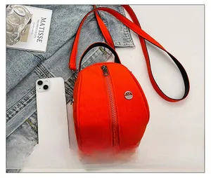 Detail of a vibrant orange nylon shell crossbody bag with metal zipper and strap details