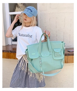 Detail of mint green canvas tote bag with front utility pockets and adjustable strap