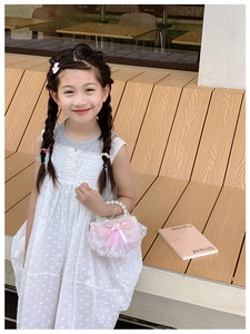 Fillette avec sac à nœud rose et poignée en perles assise sur un escalier en bois