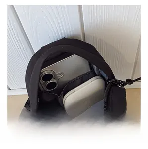 Detail showing internal capacity of black nylon chest bag with phone and earbuds