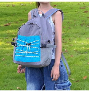 Outdoor shot of a kids large-capacity contrast backpack with blue zipper pocket and drawstrings