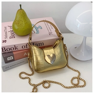 Close-up of gold crocodile-patterned mini bag with a heart-shaped metallic clasp and chain