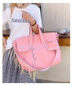 Detail of pink canvas tote bag featuring triple front pockets and decorative tassel