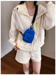 Close-up of bright blue mini chest bag with black button pocket on white athletic outfit