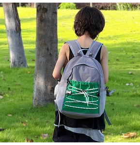 Buitenopname van een kinderrugzak van grijze stof met groene trekkoorddetails