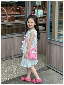 Detailed view of pink pleated shoulder bag with tulip charm on a sweet girls' outfit