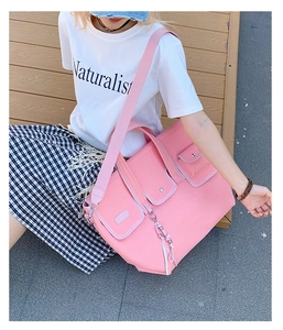 Pink canvas tote bag featuring multiple front flap pockets and adjustable shoulder strap