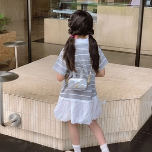 Girl in striped mesh dress wearing a silver bow-shaped shoulder bag with chain