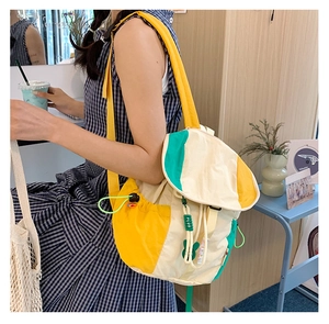Détail du sac à dos en toile bicolore avec poche latérale à cordon et breloques vertes