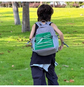 Outdoor shot of kids backpack featuring contrast color pockets and green drawstring