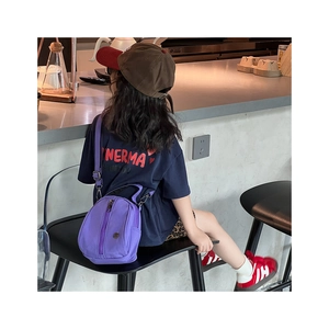 Purple nylon crossbody bag for kids shown on child model in a cafe setting