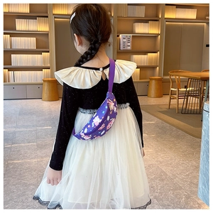 Fillette portant un sac de poitrine licorne violet dans une bibliothèque vue de dos
