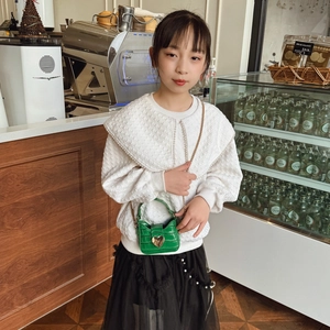 Green mini stone texture kids crossbody bag with large gold heart lock on a small model