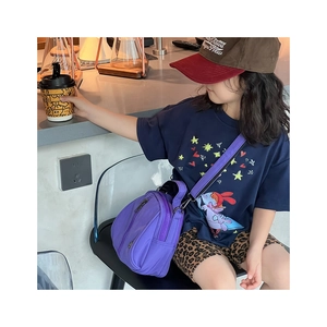 Kids purple nylon crossbody shell bag with adjustable straps in a cozy cafe setting